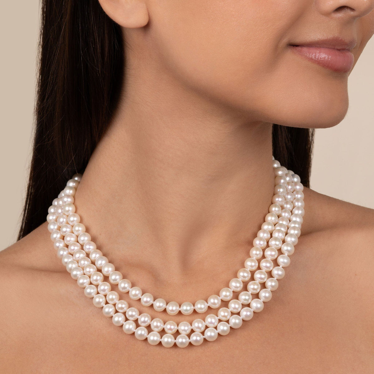 A woman wearing a triple-strand AAA white freshwater cultured pearl necklace
