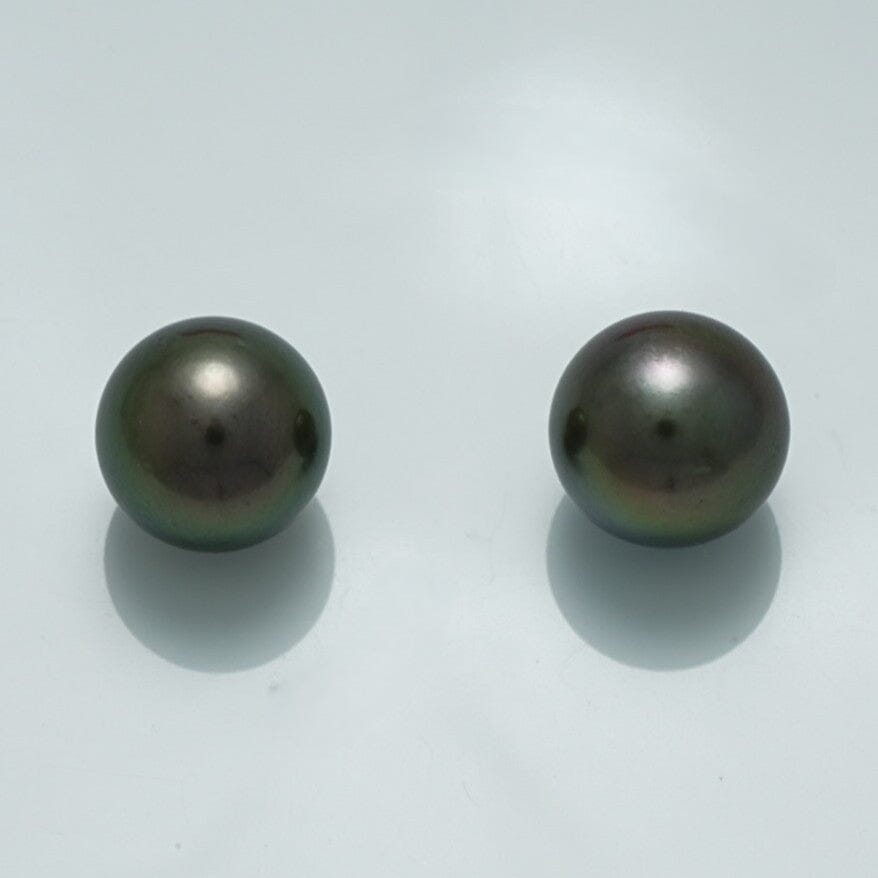 11.1 x 11.1 mm and 11.3 x 11.3 mm Fijian Round Pearl Pair in dark, lustrous colors reflecting subtle green and purple hues on a smooth surface.