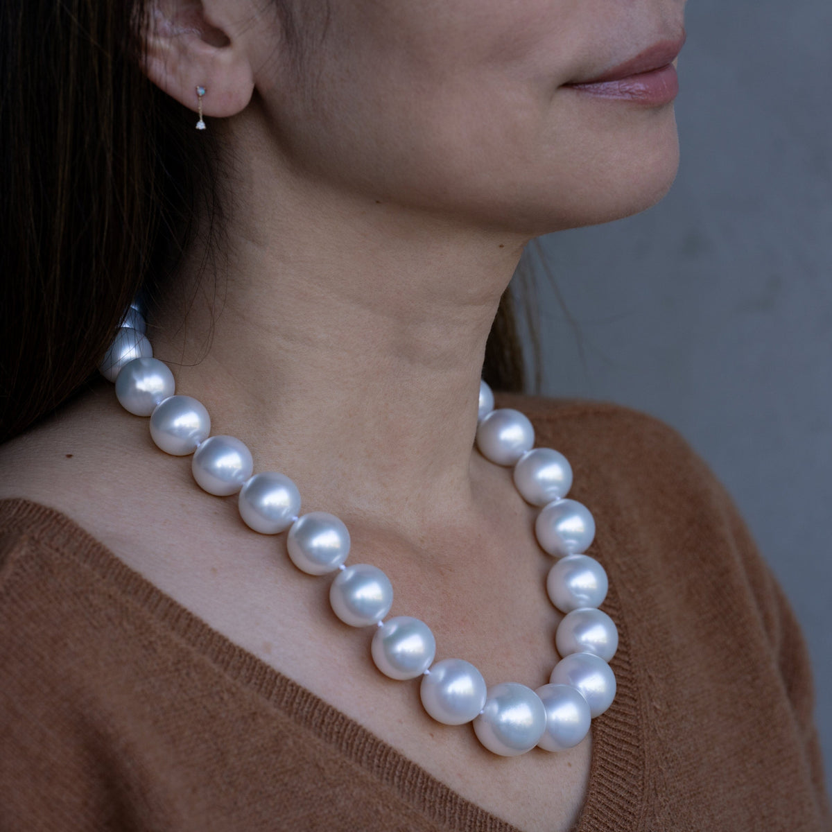 Close-up of a woman wearing a 16.0–20.2 mm AAA White South Sea Round Pearl Necklace with large, lustrous white pearls paired with a simple small pearl earring.