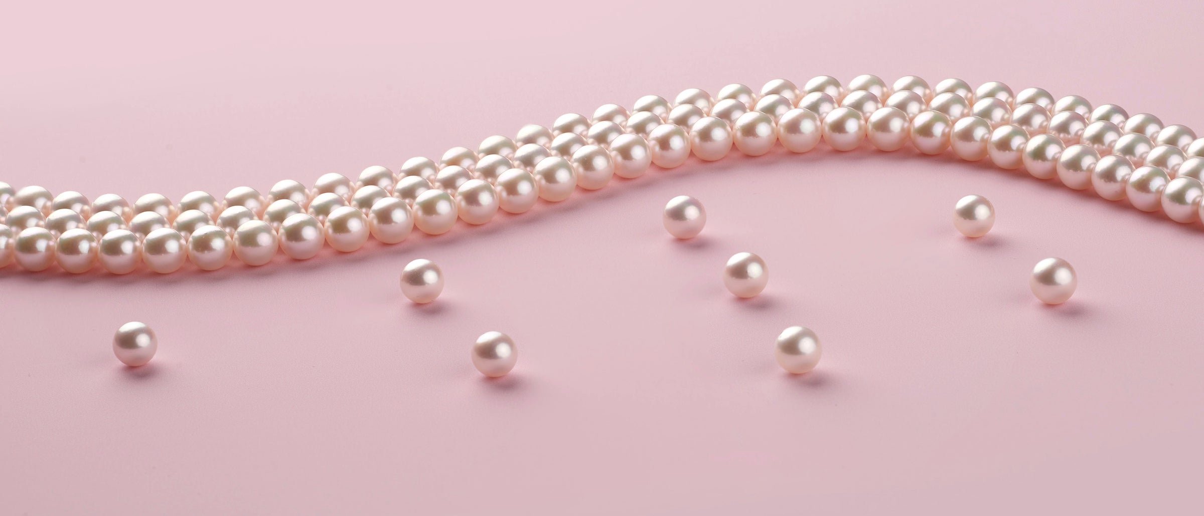 loose akoya pearls and akoya pearls strands on pink