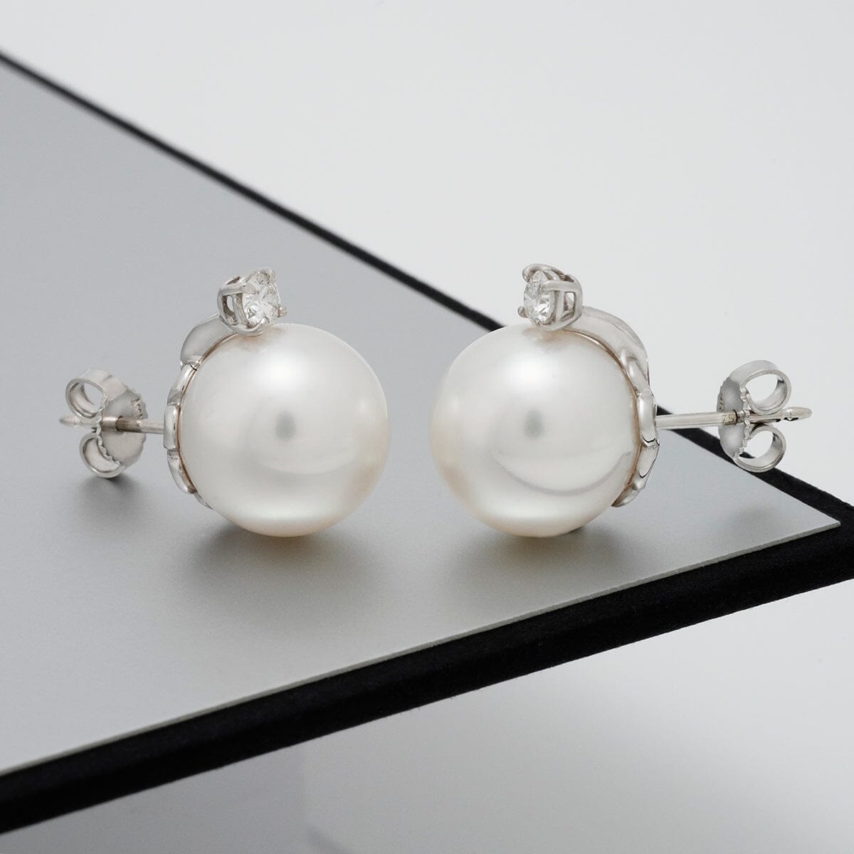 Close-up of elegant Assael Collection: 13.0 mm White South Sea Pearl and Diamond Earrings featuring lustrous white pearls set with sparkling diamonds on 14K white gold posts.