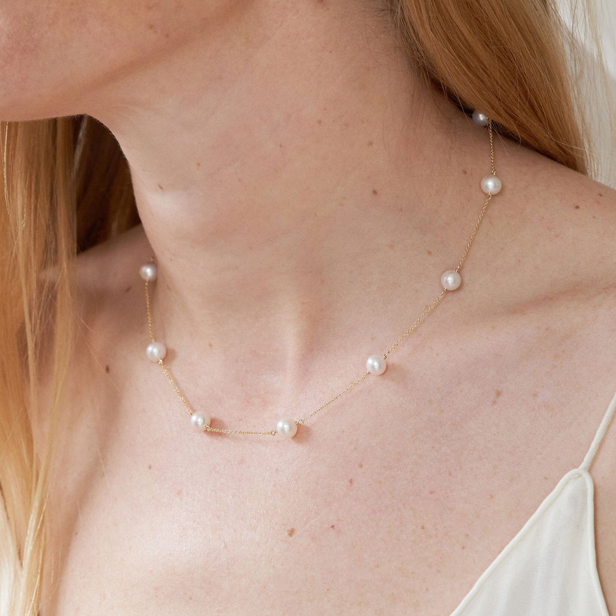 A white Freshadama pearl tin cup necklace with gold chain, displayed on model