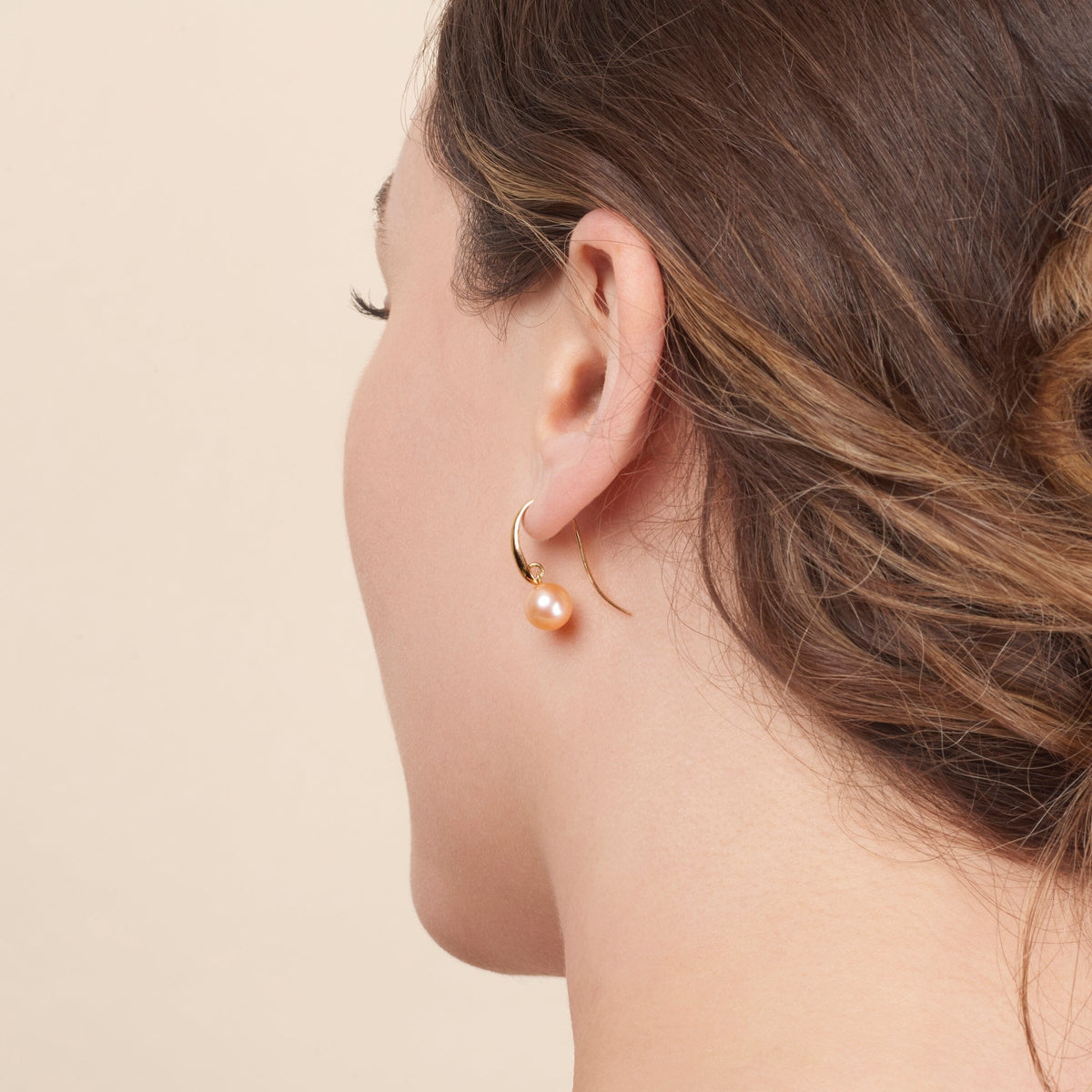 Woman wearing a single elegant hoop earring featuring a pink freshwater pearl, showcasing the Cascade Collection 8.5-9.0 mm Pink Freshadama Pearl Earrings style.