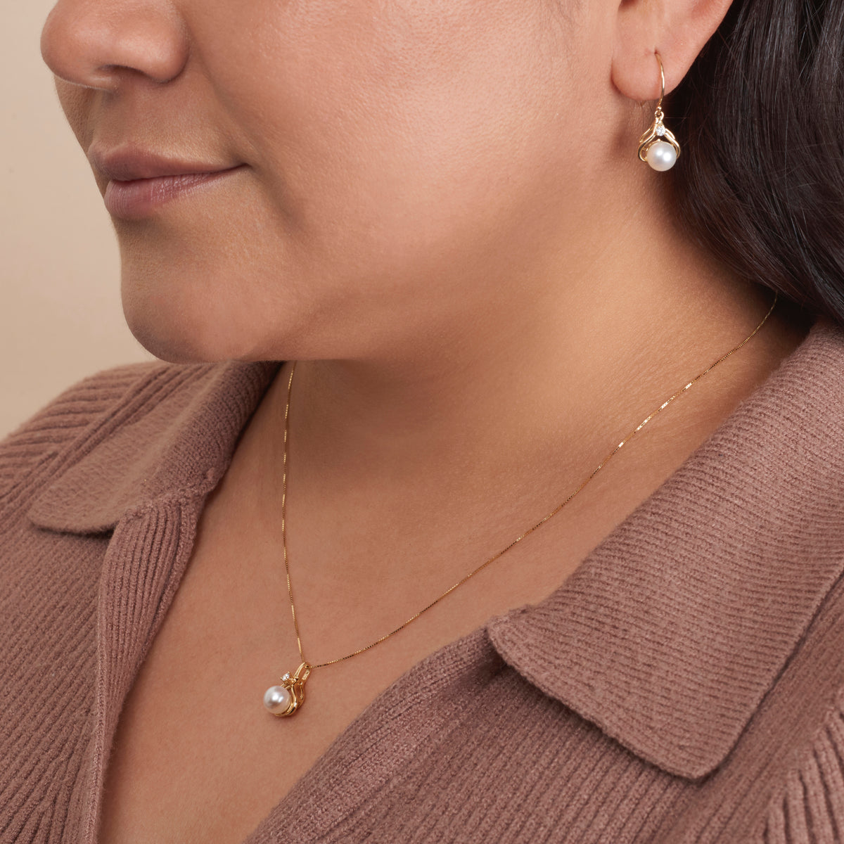 Woman wearing a delicate gold necklace with the Tiara Collection 6.5-7.0 mm White Freshadama Pearl and Diamond Pendant, paired with matching pearl earrings.