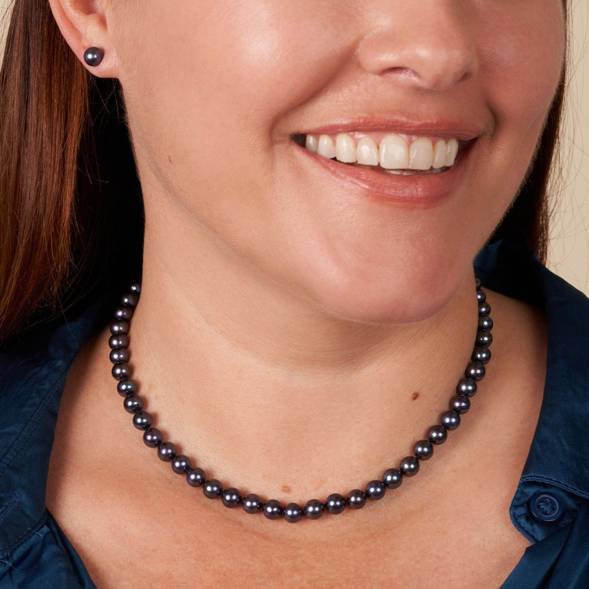 Close-up of a smiling woman wearing a 6.5-7.0 mm AAA Black Freshwater Pearl Necklace paired with matching black pearl stud earrings.