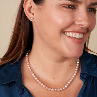 Woman wearing 6.5-7.0 mm AAA Lavender Freshwater Pearl Stud Earrings paired with a matching lavender freshwater pearl necklace and a blue blouse.