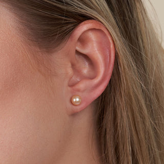 Close-up of an ear wearing a 6.5-7.0 mm AAA Pink to Peach Freshwater Pearl Stud Earrings with a soft, natural pearl luster and subtle pink to peach gradient.
