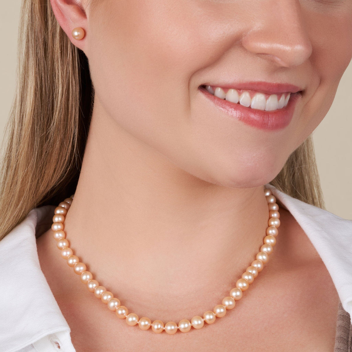 Woman wearing 6.5-7.0 mm AAA Pink to Peach Freshwater Pearl Necklace with matching pearl stud earrings, showcasing soft pastel tones and elegant style.