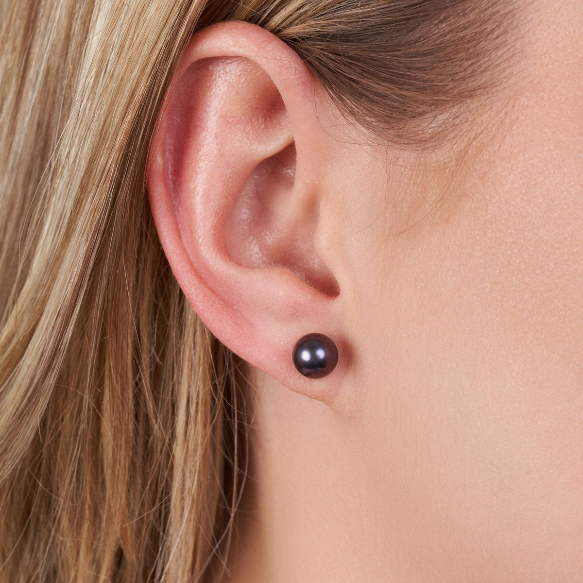 Close-up of a woman wearing 7.5-8.0 mm AAA Black Freshwater Pearl Stud Earrings, showcasing the elegant deep black luster and smooth round shape on her ear.