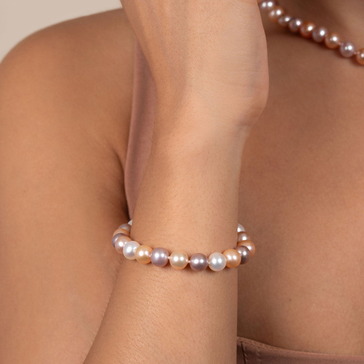 Close-up of a wrist wearing a 7.5-8.0 mm Multicolor Freshwater AAA Pearl Bracelet featuring lustrous pearls in soft pink, lavender, white, and peach tones, elegantly styled.