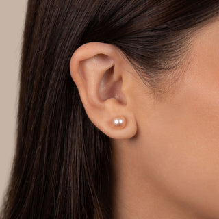 Close-up of an ear wearing a 7.5-8.0 mm AAA Pink to Peach Freshwater Pearl Stud Earrings, showcasing the soft luster and subtle color gradient of the pearl against smooth skin.