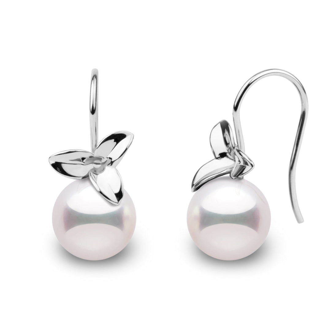 A pair of perfectly round Akoya pearl earrings with a floral design.