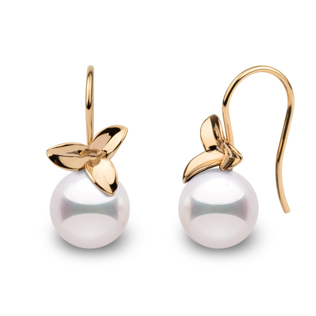 A pair of perfectly round Akoya pearl earrings with a floral design.