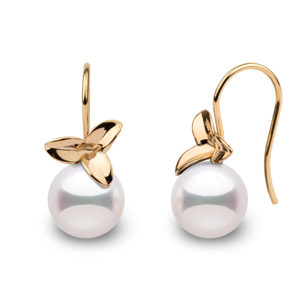 A pair of perfectly round Akoya pearl earrings with a floral design.