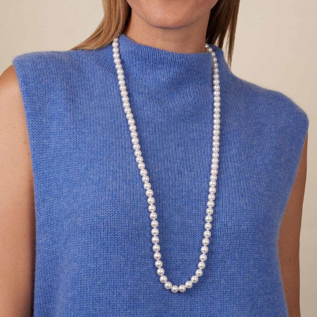Woman wearing a long, elegant 8.5-9.0 mm 35 Inch AA+ Blush White Silver Rose Tone Akoya Pearl Necklace over a soft blue sleeveless top.