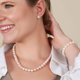 Smiling woman wearing a 3-Piece Set of 8.5-9.0 mm White Freshadama Freshwater Pearls including a necklace, bracelet, and stud earrings showcasing classic white pearls.