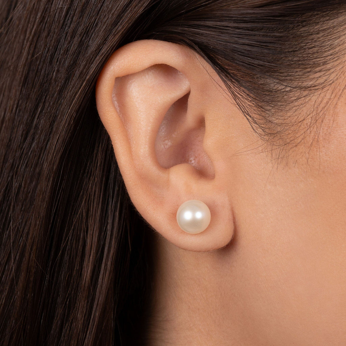 Close-up of a woman’s ear wearing 8.5-9.0 mm AAA White Freshwater Pearl Stud Earrings, showcasing the smooth, lustrous white pearl on the earlobe.
