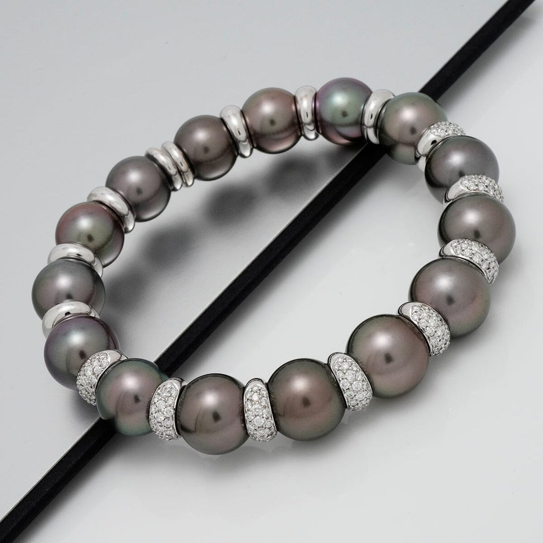 Assael Collection: 11.0-12.7 mm Tahitian Pearl and Diamond Bracelet featuring lustrous dark Tahitian pearls separated by sparkling diamond-encrusted spacers on a sleek surface.
