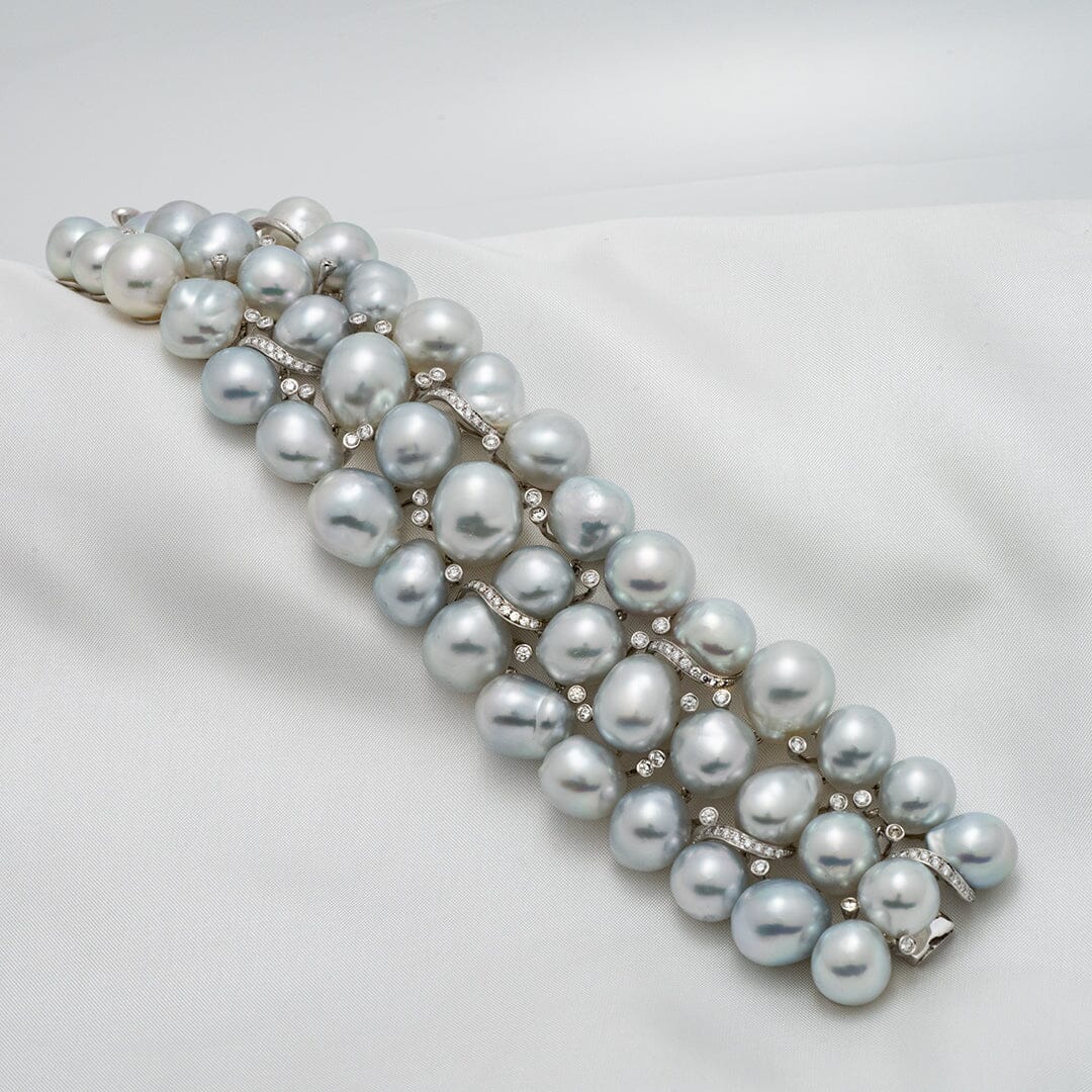 Assael Collection: 10.0–13.0 mm Baroque White South Sea Pearl Bracelet featuring lustrous, uniquely shaped white pearls with diamond-accented links displayed on a soft fabric background.
