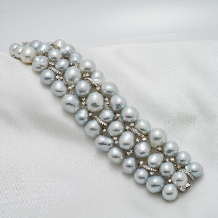 Assael Collection: 10.0–13.0 mm Baroque White South Sea Pearl Bracelet featuring lustrous, uniquely shaped white pearls with diamond-accented links displayed on a soft fabric background.
