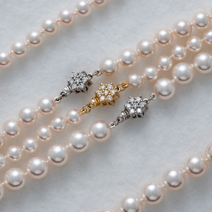 Close-up of three elegant Christina Assael Select Akoya Strands pearl necklaces featuring lustrous white pearls and delicate diamond-accented clasps in gold and silver tones.