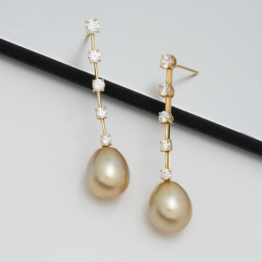 Assael Collection: 11.2 x 13.6 mm Golden South Sea Pearl and Diamond Earrings featuring elegant golden pearls hanging from a slender gold bar adorned with sparkling diamonds.