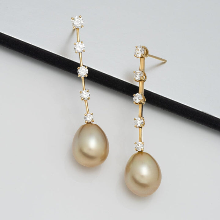 Assael Collection: 11.2 x 13.6 mm Golden South Sea Pearl and Diamond Earrings featuring elegant golden pearls hanging from a slender gold bar adorned with sparkling diamonds.