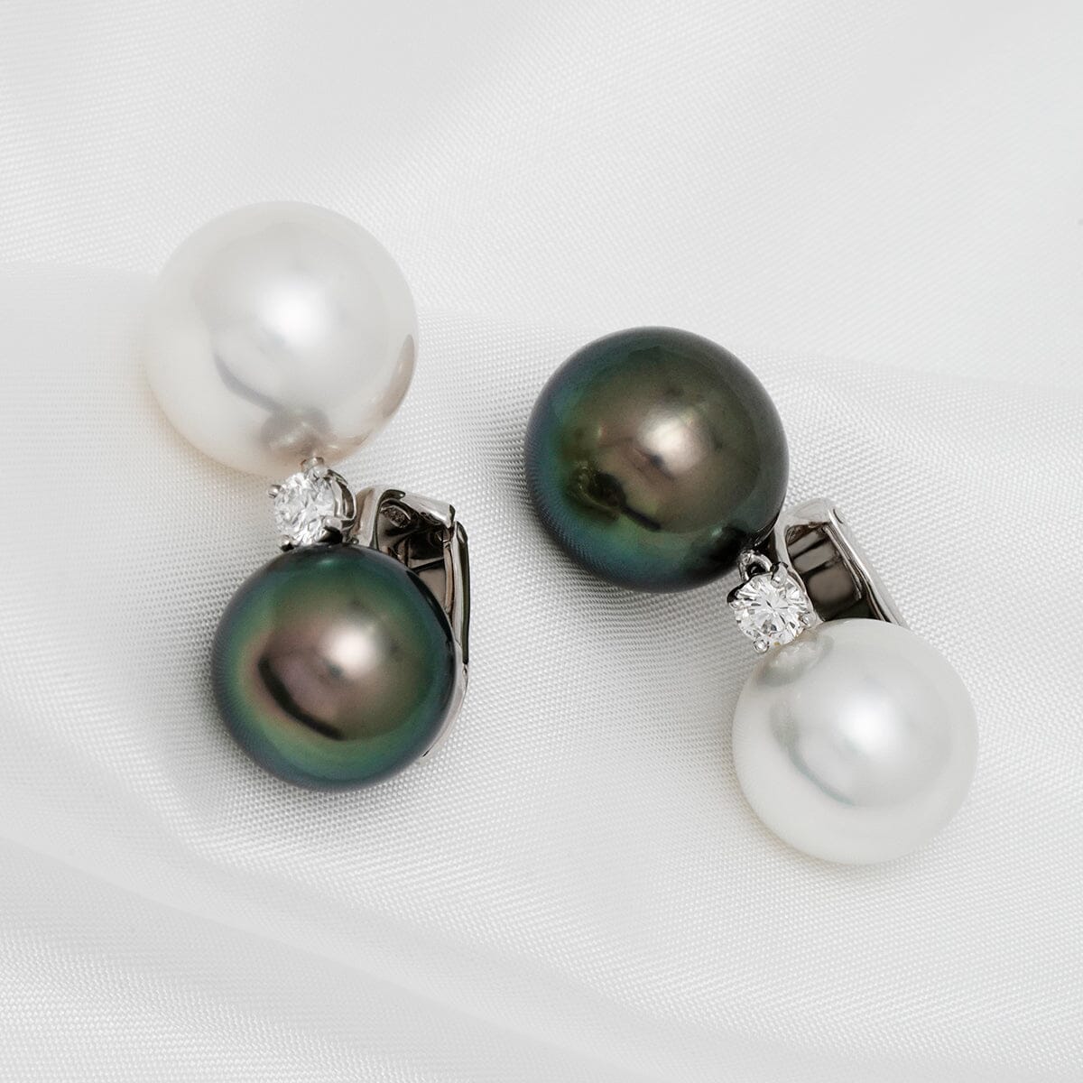 Assael Collection: 13 mm and 14 mm Tahitian & South Sea Pearl and Diamond Earrings featuring classic white and black pearls accented with sparkling diamonds on a 14K white gold setting.