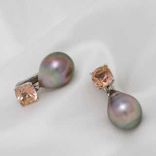 Pair of Assael Collection: 16.3x13.0 mm Tahitian Pearl and Tourmaline Earrings featuring lustrous black pearls and soft peach tourmaline gemstones on a white fabric background.
