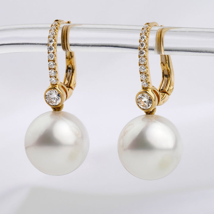 Assael Collection: 11.3 & 11.4 mm White South Sea Pearl and Diamond Earrings featuring round white pearls suspended from gold hoops encrusted with small sparkling diamonds.