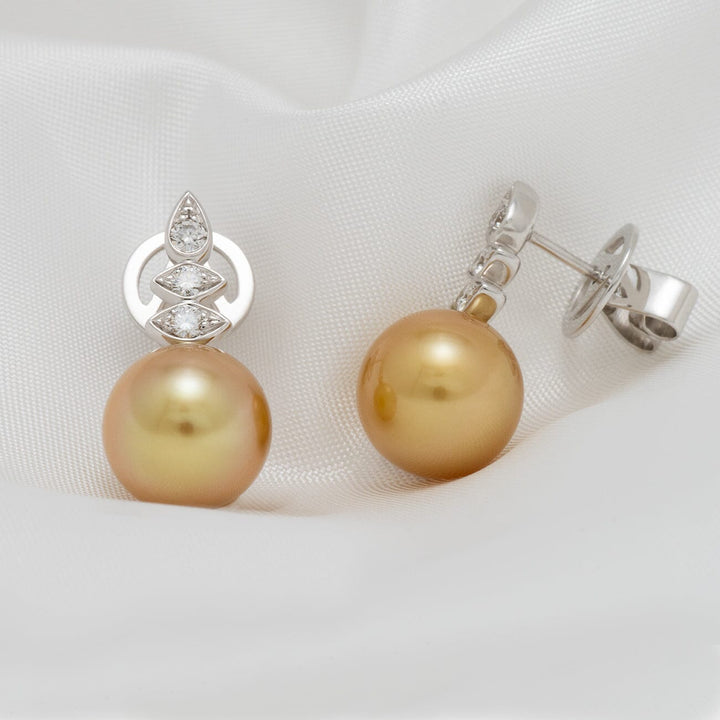 Assael Collection: 10.0–10.5 mm Golden South Sea Pearl and Diamond Earrings featuring lustrous golden pearls with sparkling diamond accents on a white metal setting against a soft white fabric background.