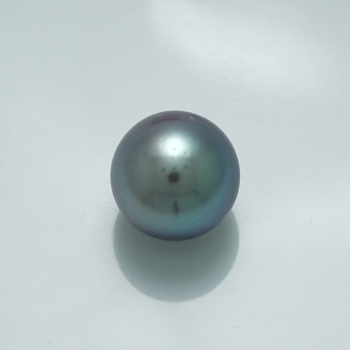 13.3 x 13.3 mm Fijian Pearl with a smooth surface and lustrous dark gray-green hues, reflecting subtle iridescent colors typical of fine cultured pearls.