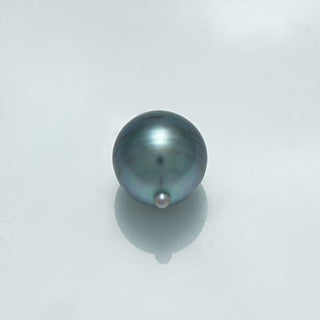 11.5 x 10.0 mm Fijian Drop Pearl with a smooth, lustrous surface showcasing natural hues of dark gray and subtle iridescent tones on a light background.