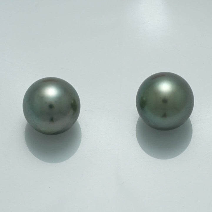 10.4 x 10.4 mm and 10.3 x 10.2 mm Fijian Pearl Pair with smooth, lustrous surfaces and subtle dark greenish-gray hues on a plain light background.