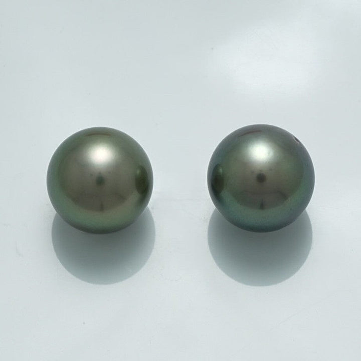 13.0 x 13.0 mm and 13.0 x 13.0 mm Fijian Round Pearl Pair featuring two lustrous dark green cultured pearls with smooth surfaces against a light background.
