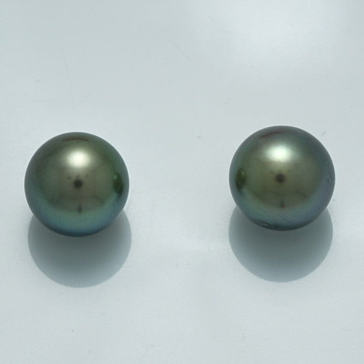 10.3 x 10.3 mm and 10.5 x 10.4 mm Fijian Pearl Pair showcasing round, lustrous dark pearls with subtle green and blue overtones on a light background.