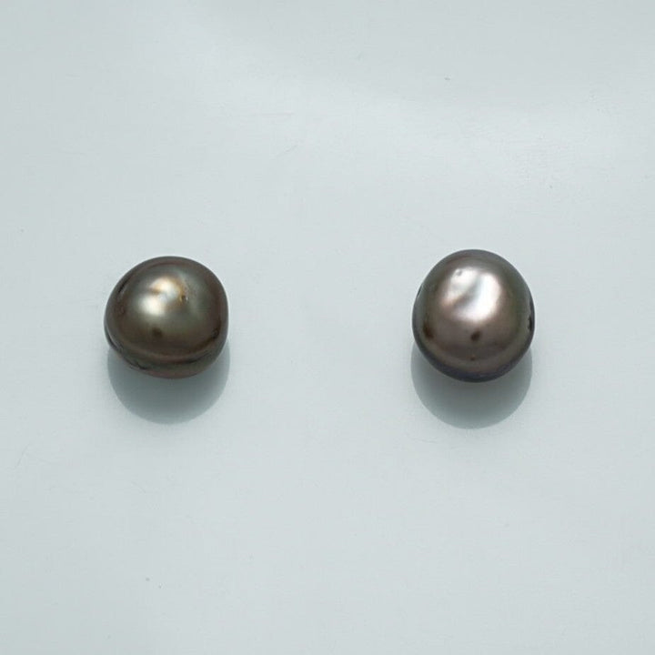 10.1 x 8.7 mm and 9.3 x 9.0 mm Fijian Keshi Button Pearl Pair showcasing natural luster and unique shapes with a subtle metallic gray and lavender hue on a pale background.
