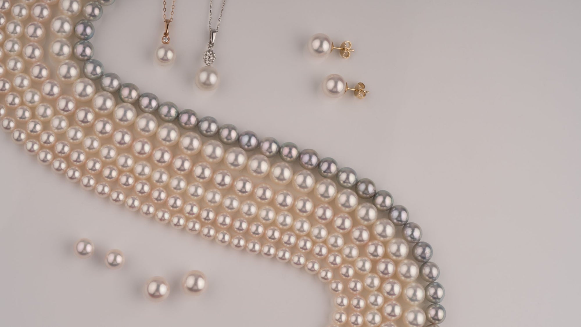 Pearl necklace with matching earrings on a light gray background
