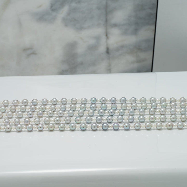 2.0-5.5 mm Intense Blue Ombre Akoya Semi-Round Pearl Strand displayed against a white and marble background, showcasing smooth, lustrous pearls with subtle blue and silver hues.