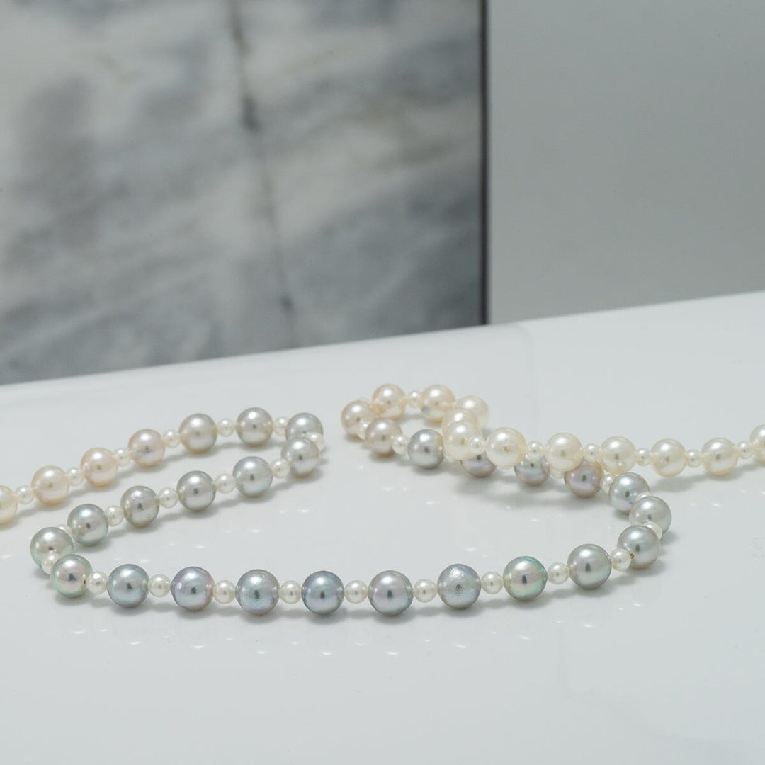 2.0-5.5 mm Intense Blue Ombre Akoya Semi-Round Pearl Strand displayed on a polished surface, showcasing subtle color variation and lustrous cultured pearls in a refined setting.