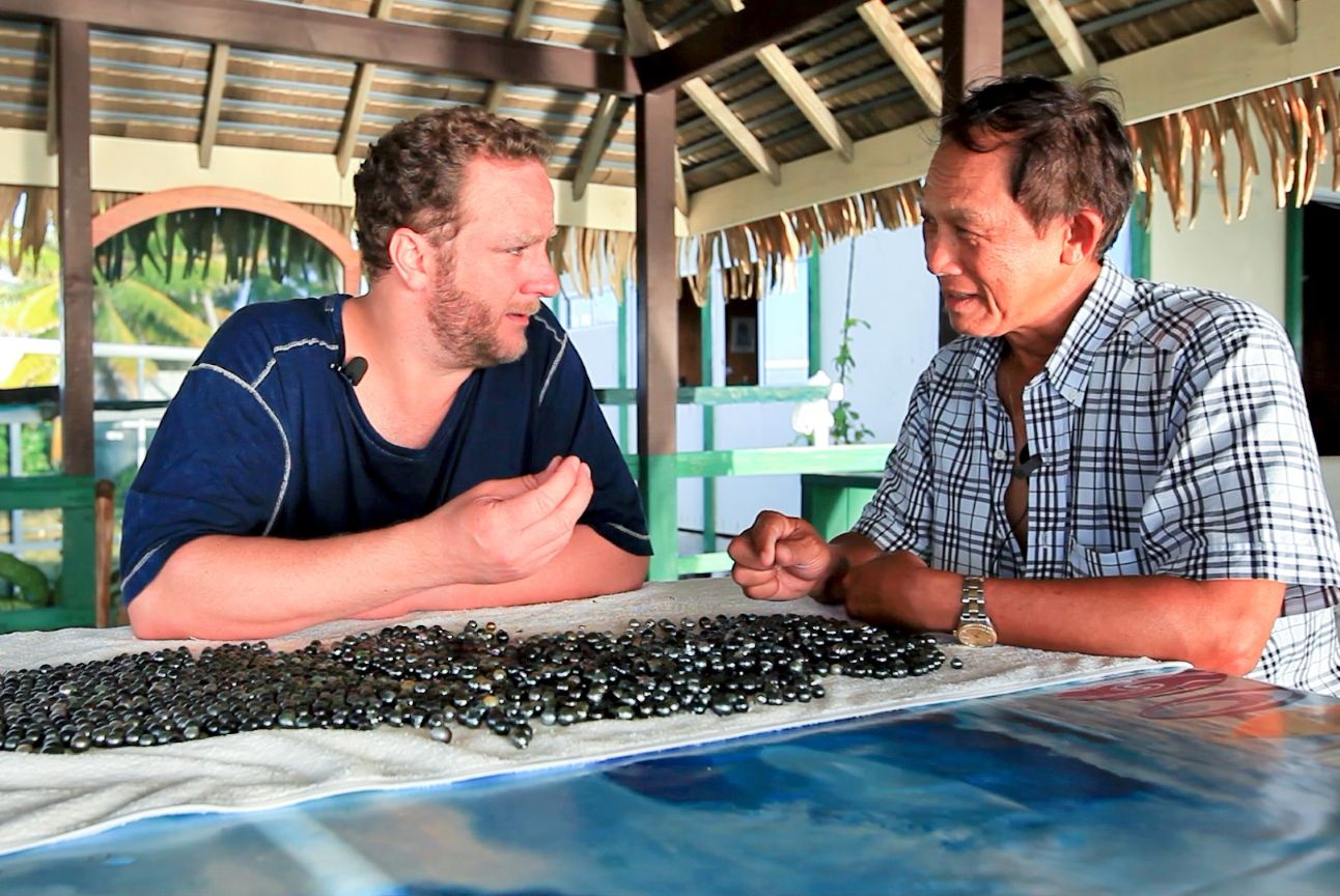 Pearl Paradise founder Jeremy Shepherd examining a Tahitian pearl harvest with a pearl farmer