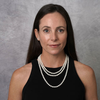 Woman wearing a 3-Piece Set of 6.5-7.0 mm AAA White Akoya Pearls necklace and matching pearl stud earrings, styled with a black sleeveless top against a neutral background.