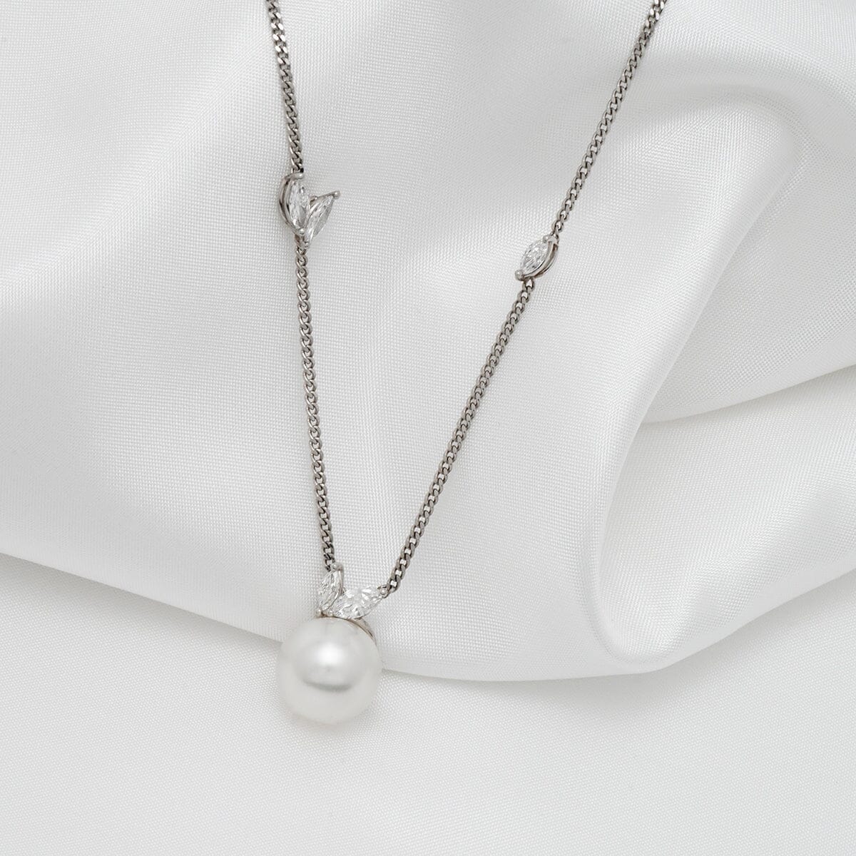 Assael Collection: 10.5-11.0 mm White South Sea Pearl and Diamond Pendant featuring a lustrous white pearl and delicate diamond accents on a fine silver chain against a soft white fabric background.