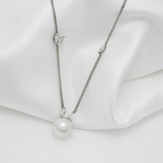 Assael Collection: 10.5-11.0 mm White South Sea Pearl and Diamond Pendant featuring a lustrous white pearl and delicate diamond accents on a fine silver chain against a soft white fabric background.