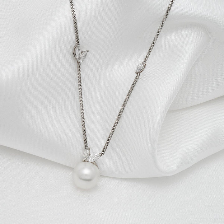 Assael Collection: 10.5-11.0 mm White South Sea Pearl and Diamond Pendant featuring a lustrous white pearl and delicate diamond accents on a fine silver chain against a soft white fabric background.