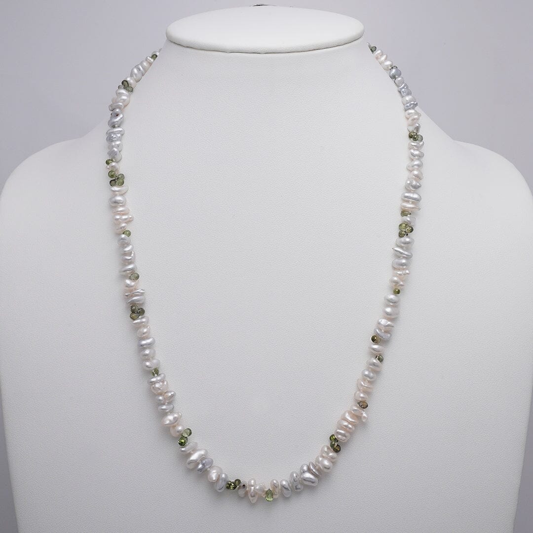 Assael Collection: 5.5–10.3 mm White South Sea Keshi Pearl and Green Sapphire Necklace featuring lustrous white pearls interspersed with small green sapphire gemstones on a white display bust.