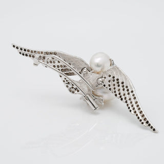 Assael Collection: 14.0 mm White South Sea Pearl, Diamond and Sapphire Brooch featuring a detailed 14K white gold wing design with white pearl center accented by diamonds and sapphires.