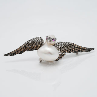 Assael Collection: 14.0 mm White South Sea Pearl, Diamond and Sapphire Brooch designed as a bird with outstretched wings set with diamonds and sapphires.