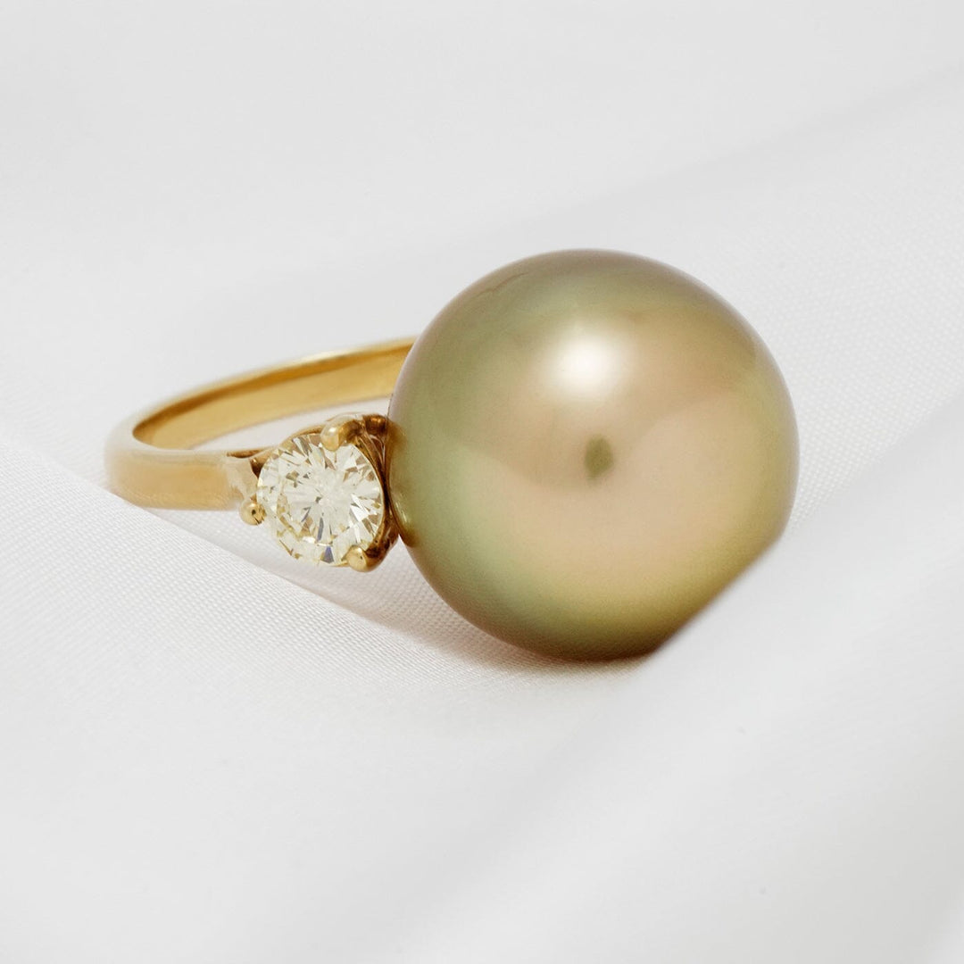 Assael Collection: 15.4 mm Golden South Sea Pearl and Diamond Ring featuring a large golden South Sea pearl set beside a sparkling diamond on a gold band against a white background.
