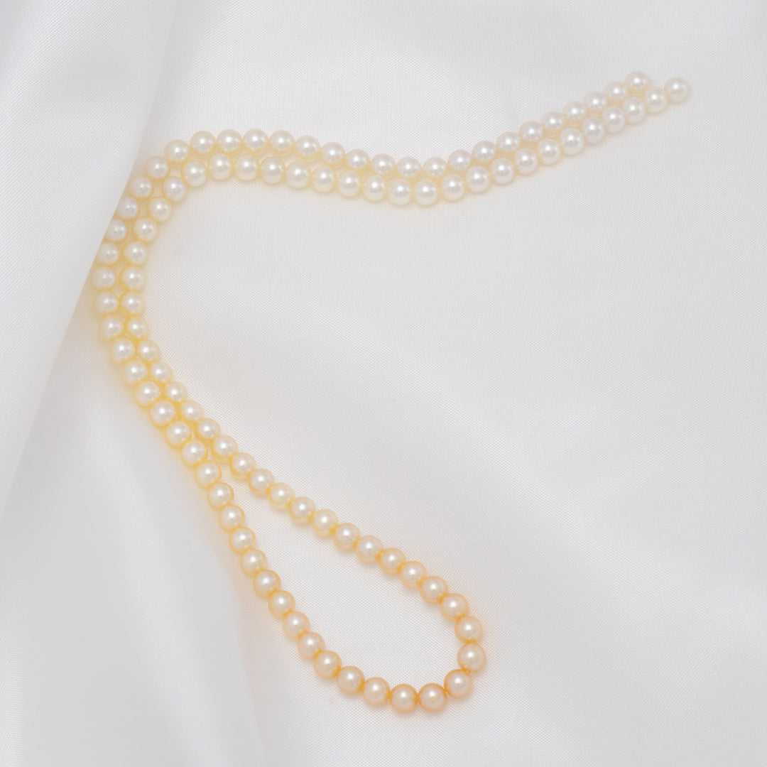 TF-22: 4-4.5 mm Natural-color Round Akoya Ombré Pearl Strand elegantly displayed on smooth white fabric, showcasing lustrous cultured akoya pearls in a subtle ombré effect.